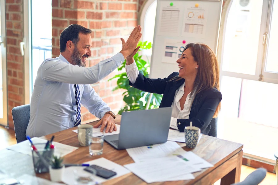 two people high fiving in an office setting