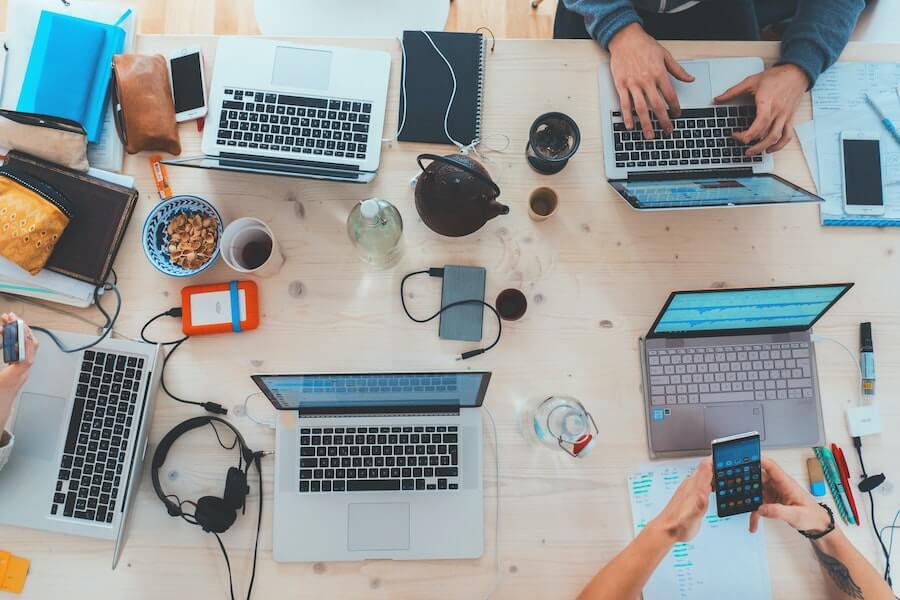 top down view of multiple people working on laptops and smartphones