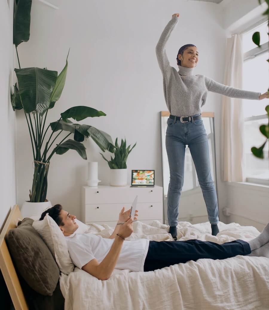 woman jumping on a bed, man lying down